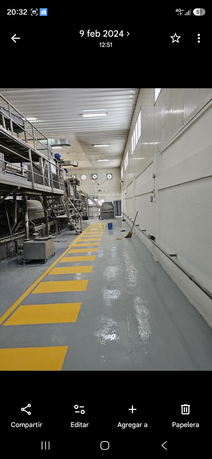 Pasillo industrial con piso gris y señalización amarilla de seguridad